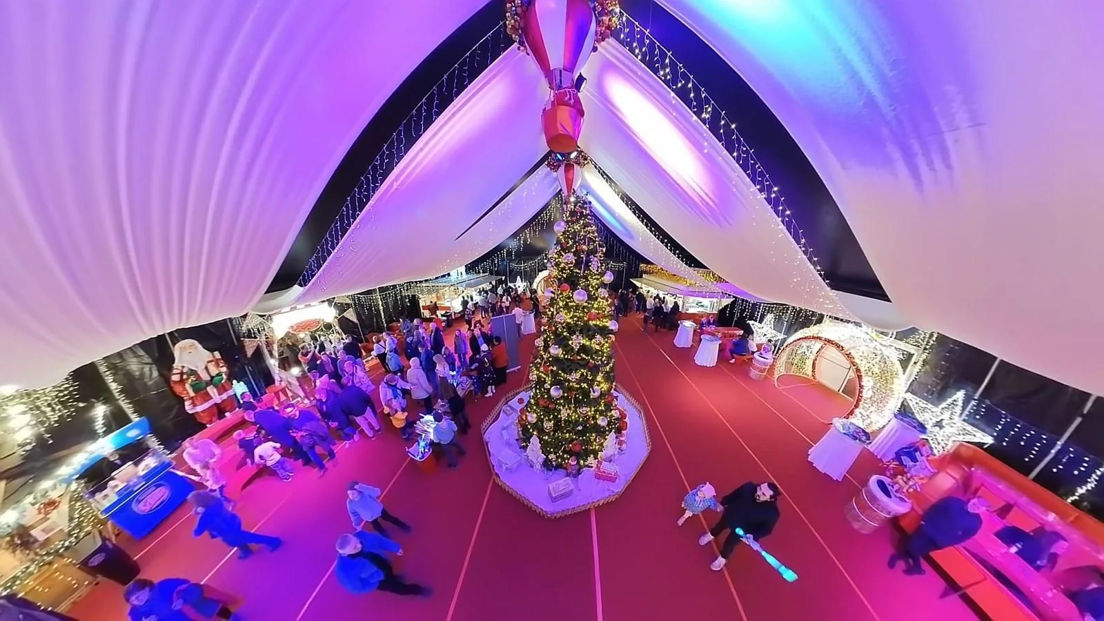 Festlich geschmücktes Foyer der Zeltstadt mit großem Weihnachtsbaum und Lichterglanz